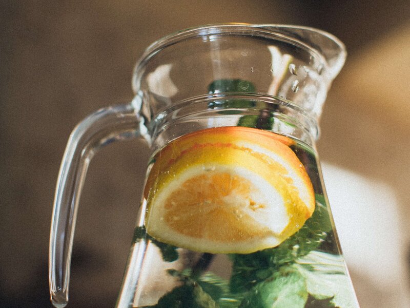 Ein Glaskrug gefüllt mit Wasser, Gurkenscheiben und Zitrone.